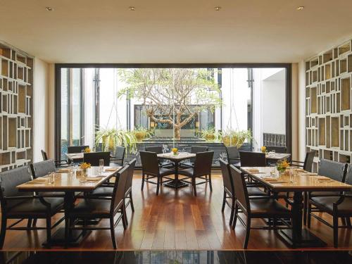 a restaurant with tables and chairs and a large window at Mövenpick Hotel Sukhumvit 15 Bangkok in Bangkok