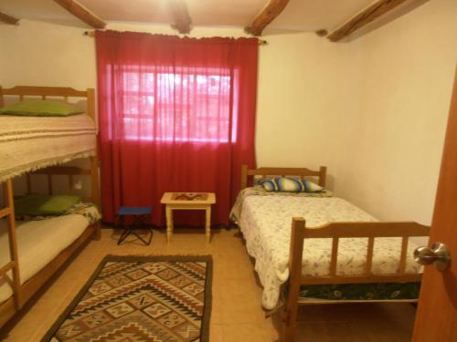 1 dormitorio con 2 camas y cortina roja en Nilo Trek House, en Chiquián