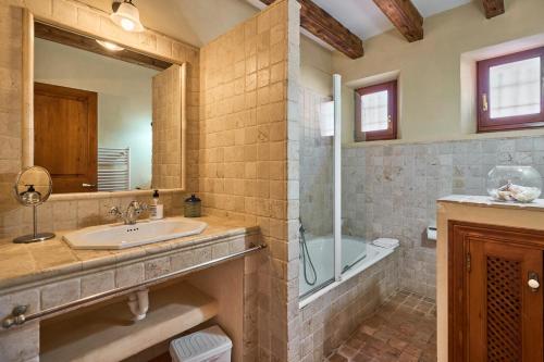 Un baño con lavabo, bañera y espejo. en Finca Penya Redona, en Alquería Blanca