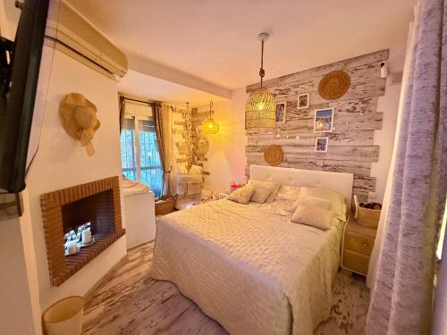 a bedroom with a white bed and a fireplace at Residencial Bajo con jardín y jacuzzi privado Calahonda Royale in Cabopino