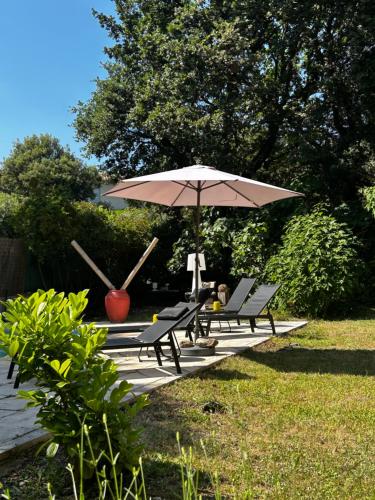 a picnic table with an umbrella and two benches at Esprit CAP FERRET in Puget