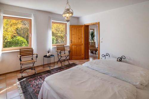 a bedroom with a bed and two chairs and windows at Naturferienwohnung Am Lautergarten in Indelhausen