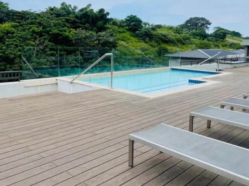 a swimming pool with two benches on a wooden deck at Zimbali Lakes Boulevard Suites 145 in Ballito