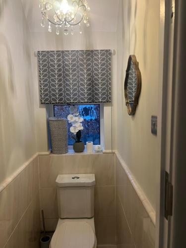 a bathroom with a toilet and a window with a chandelier at 4 BRD House, with Double Parking in Earley