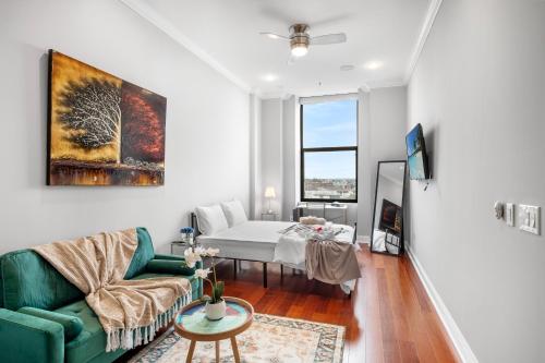 a living room with a bed and a green couch at XL Studio - Modern Studio with Rooftop Pool in Philadelphia