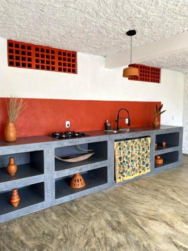 a kitchen with a gray counter and orange wall at Divina Casa in Itacaré