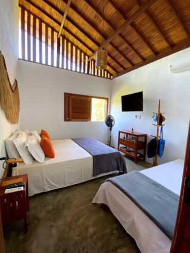 a bedroom with two beds and a television in it at Divina Casa in Itacaré