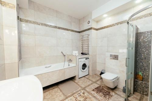 bagno con vasca, servizi igienici e lavatrice. di Apartment ultra center Sky House a Chişinău