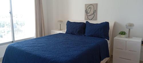 een slaapkamer met een blauw bed en een raam bij Apartamento en Boca Chica T2 707 in Boca Chica