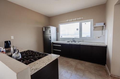cocina con nevera negra y ventana en Complejo Canto del Mar, en Balneario Mar Chiquita