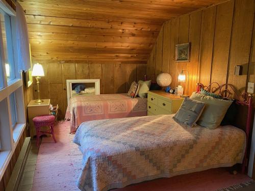 a bedroom with two beds and a wooden wall at Sunset Serenity - Incredible Home On Lake Bluff! in Frankfort