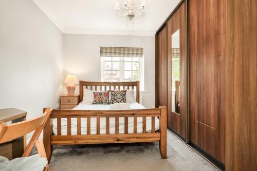 a bedroom with a wooden bed and a window at Chic 3Bed House & Garden Near Shelford High Street in Trumpington