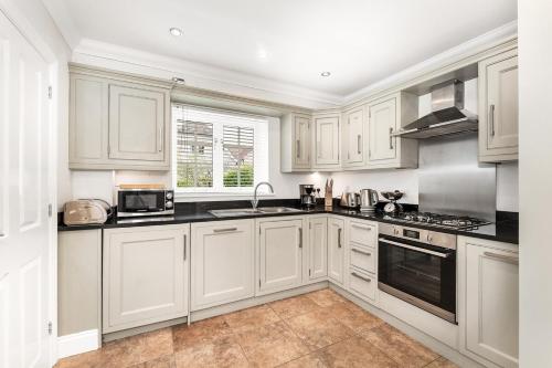 a kitchen with white cabinets and black counter tops at Chic 3Bed House & Garden Near Shelford High Street in Trumpington