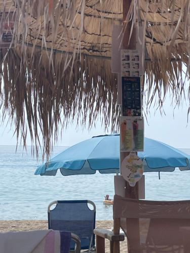 an umbrella and chairs on a beach with the ocean at Villa Sokrates in Nea Vrasna