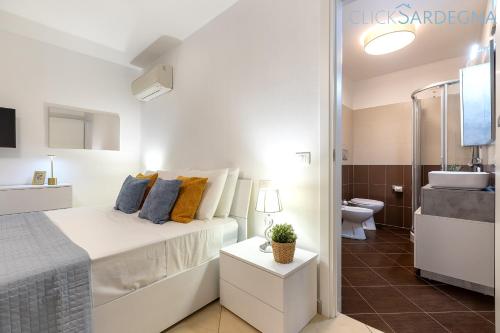 a white bedroom with a bed and a bathroom at ClickSardegna Villa Paradiso with swimming pool large garden and tennis court in Alghero
