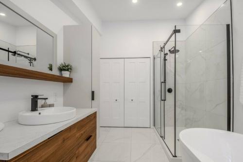 une salle de bain blanche avec lavabo et douche dans l'établissement Chalet à louer au bord d'un lac avec spa, à La Baie