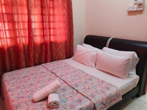 a bed with white pillows and a red curtain at Kirana Homestay Langkawi in Pantai Cenang