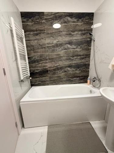 a bathroom with a white bath tub and a sink at JAD Militari Residence in Roşu