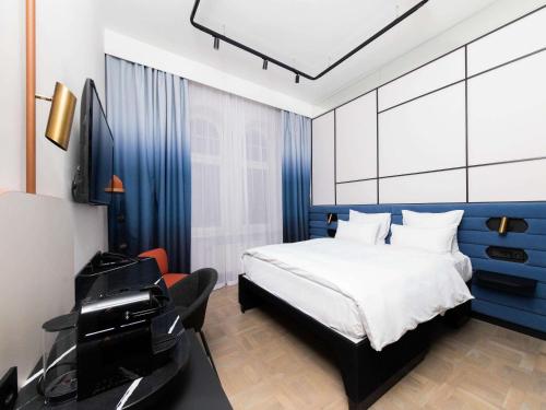 a bedroom with a bed and a desk and a television at TRIBE Riga City Centre in Rīga