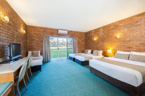 a hotel room with three beds and a television at Thurgoona Country Club Resort in Thurgoona
