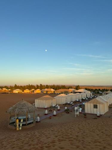 a group of tents in the sand on a beach at Oasis Desert Luxury Camp in Merzouga