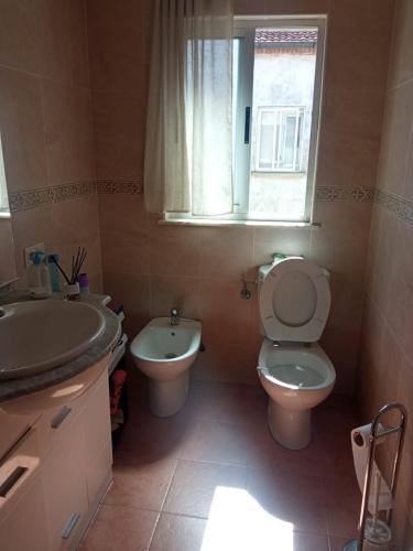 a bathroom with a sink and a toilet and a window at Acogedora habitación privada en piso familiar con baño compartido in Salamanca