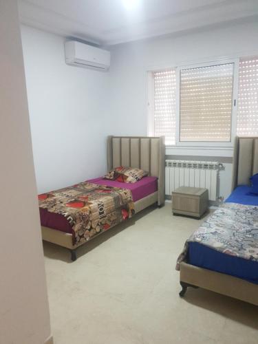a bedroom with two beds and a window at S2 lux jardin carthage in Tunis