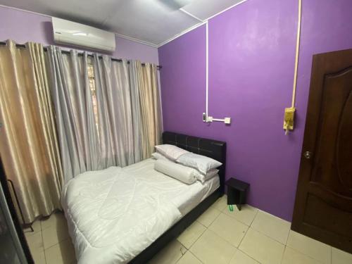 a bedroom with a bed with a purple wall at Anwar Kluang Homestay in Kluang