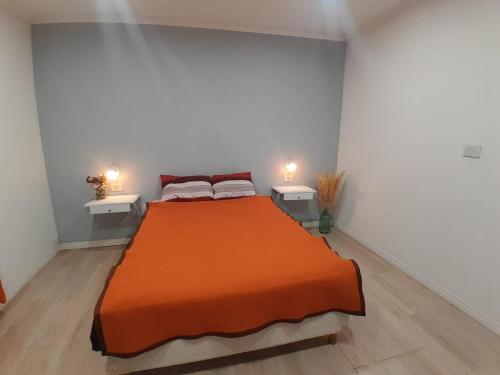 een slaapkamer met een groot oranje bed en 2 tafels bij Cabaña LuMa in San Rafael