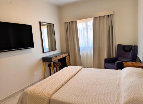 a hotel room with a bed and a chair and a television at Family House in Limassol
