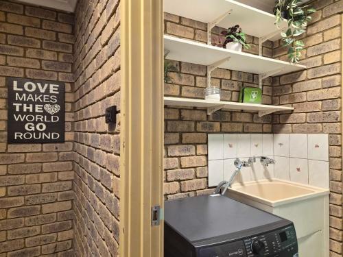 a kitchen with a brick wall and a sink at Tweebine Villas in Utakarra