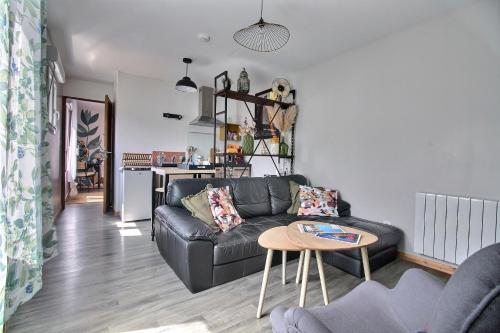ein Wohnzimmer mit einer schwarzen Couch und einem Tisch in der Unterkunft Appartement T2 indépendant au coeur de la ville in Bourges