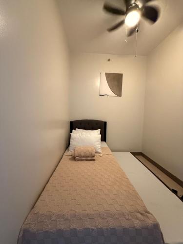 Ce lit se trouve dans un dortoir doté d'un ventilateur de plafond. dans l'établissement Urban Oasis 2BR Condo with Multiple Pools at SMDC Charm Residences, à Manille