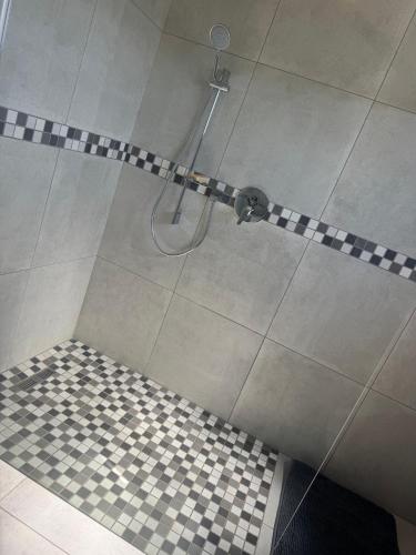 a shower with a black and white checkered floor at WeMvula Guesthouse in Mtubatuba