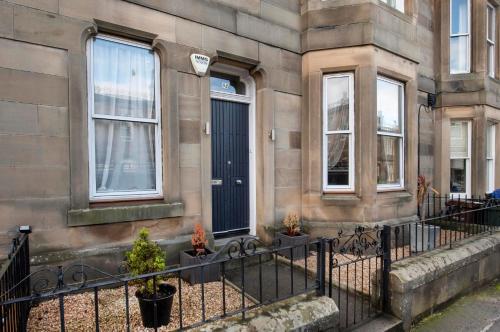 a building with a fence and some plants in front of it at Roomy home 1 level Free Parking in Edinburgh