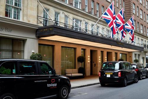 two cars parked in front of a building with british flags at The May Fair, A Radisson Collection Hotel, Mayfair London in London