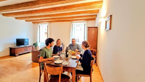 eine Gruppe von Menschen, die um einen Tisch herum sitzen in der Unterkunft LUXURY -JACUZZI- FLAT 100mq, elegante e storico, nel borgo medievale in Trient