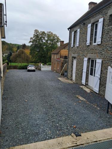 a driveway with a car parked in front of a house at Chambre chez l'habitant in Pont-d'Ouilly