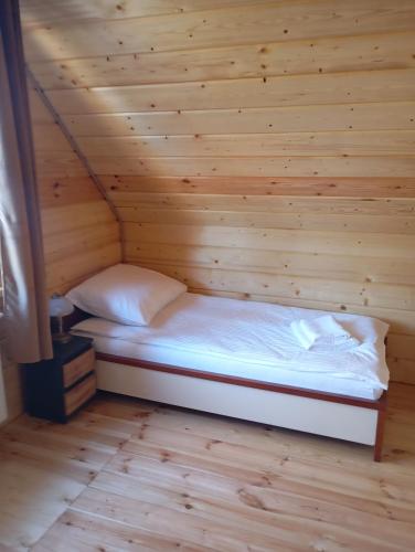 a bed in a room with a wooden wall at Apartament Szumi las in Białowieża