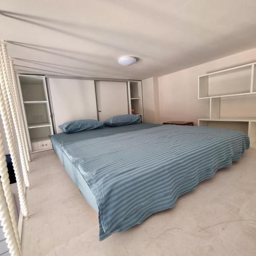 une chambre avec un grand lit avec des draps bleus dans l'établissement Tivat Cocoon Studio, à Tivat