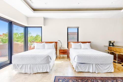 two beds in a white room with windows at Red Rock Suite in Santa Clara