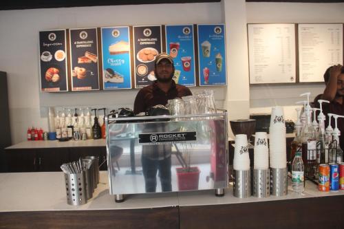 a man standing behind a counter in a bar at Hotel Blue Castle International Two in Pāksey