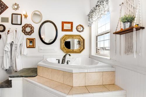 een witte badkamer met een bad en een spiegel bij The Marietta at Judith Ann Inn in Oyhut