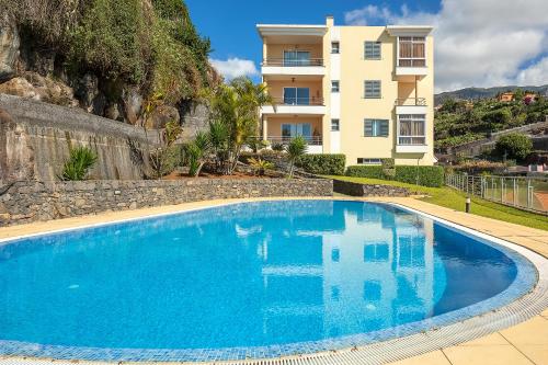 a large blue swimming pool in front of a building at Calheta, Sun, Sea & Pool in Calheta