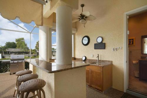 a kitchen with a counter with stools and some windows at Villa Savona in Cape Coral