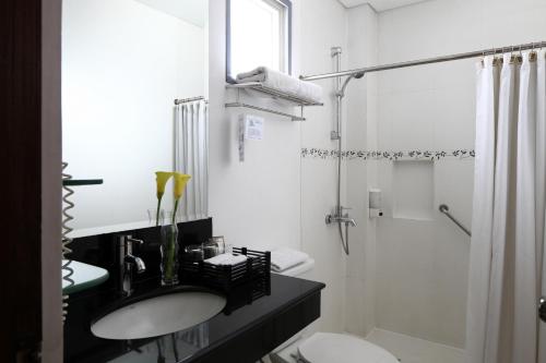 biała łazienka z umywalką i prysznicem w obiekcie Manila Lotus Hotel w mieście Manila