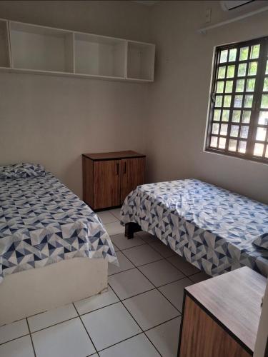 een slaapkamer met twee bedden en een raam bij Apartamento térreo com 2 quartos e jardim in Teresina