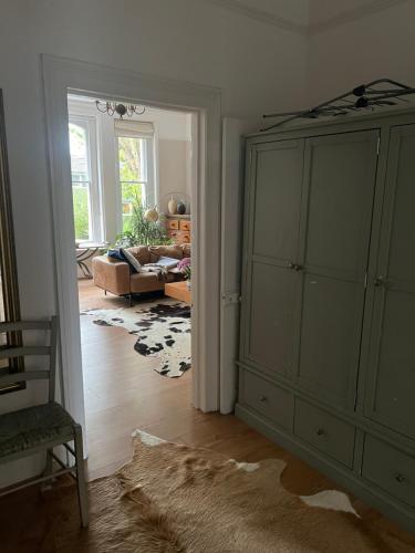un salon avec une grande armoire verte et un canapé dans l'établissement Large garden-view room, 20 min from Central London, in a stylish period property in Lee, with free parking and a friendly Jack Russell, à Londres