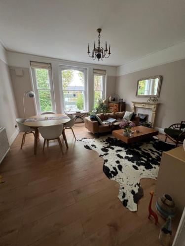 a living room with a table and a cow rug at Double room near Blackheath, 17 min from Central London, a stylish period property, with free parking in London