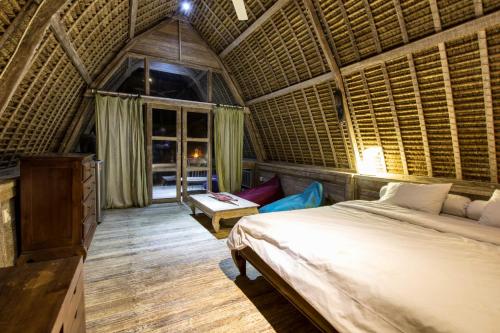 a bedroom with a bed in a straw roofed room at Gipsy Beach Bungalows in Sekotong